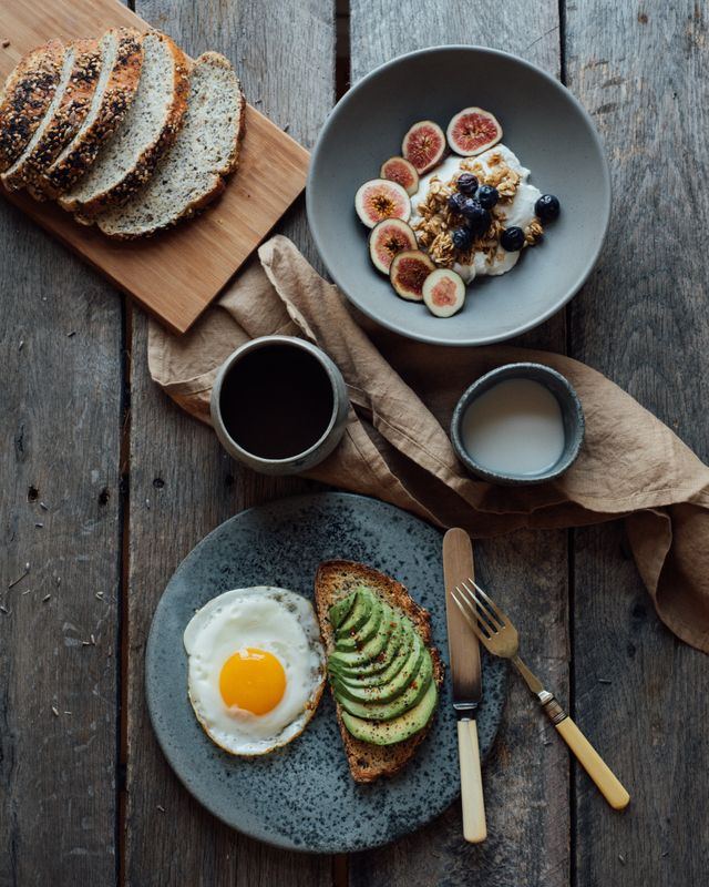 Breakfast table with toast, fruit, yogurt, coffee, and milk.